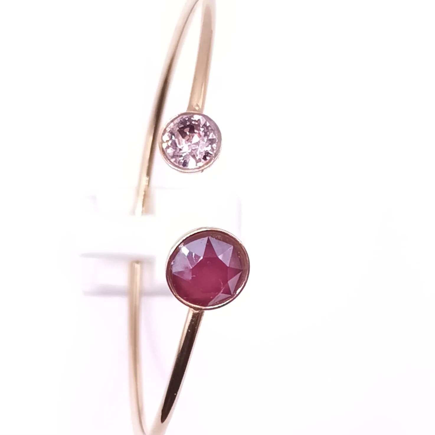 Bracelet jonc doré ouvert à cristaux grenat et rose pâle - vue d'ensemble sur son présentoir blanc
