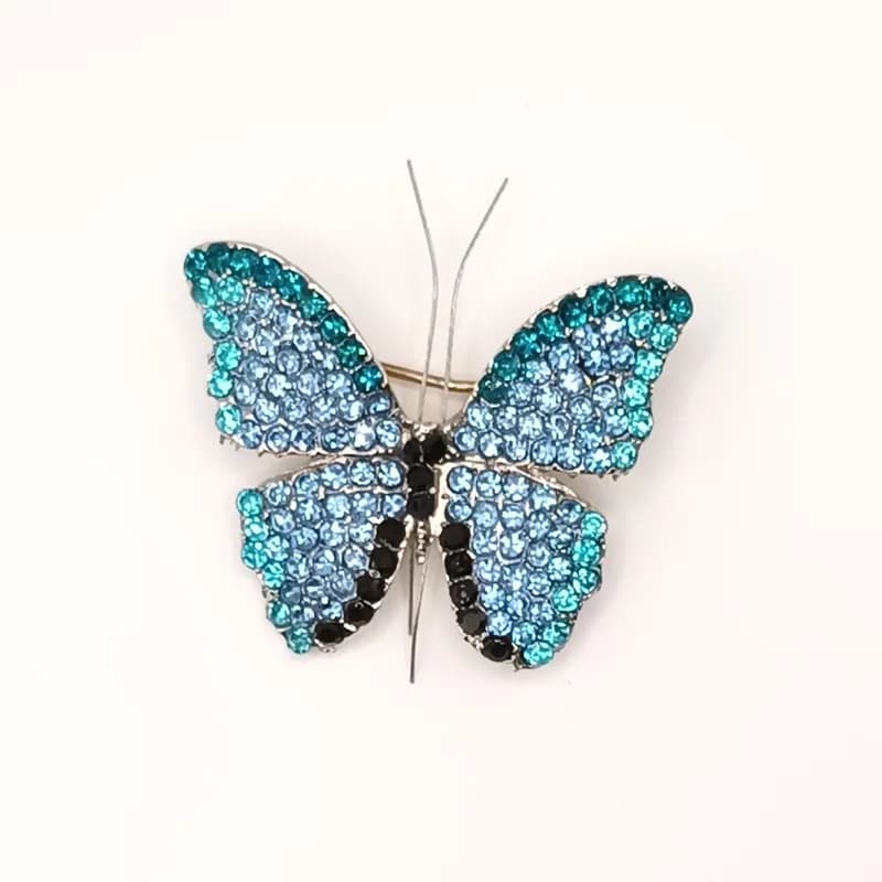 Broche papillon pavée de pierres scintillantes bleues et turquoise vue de face.
