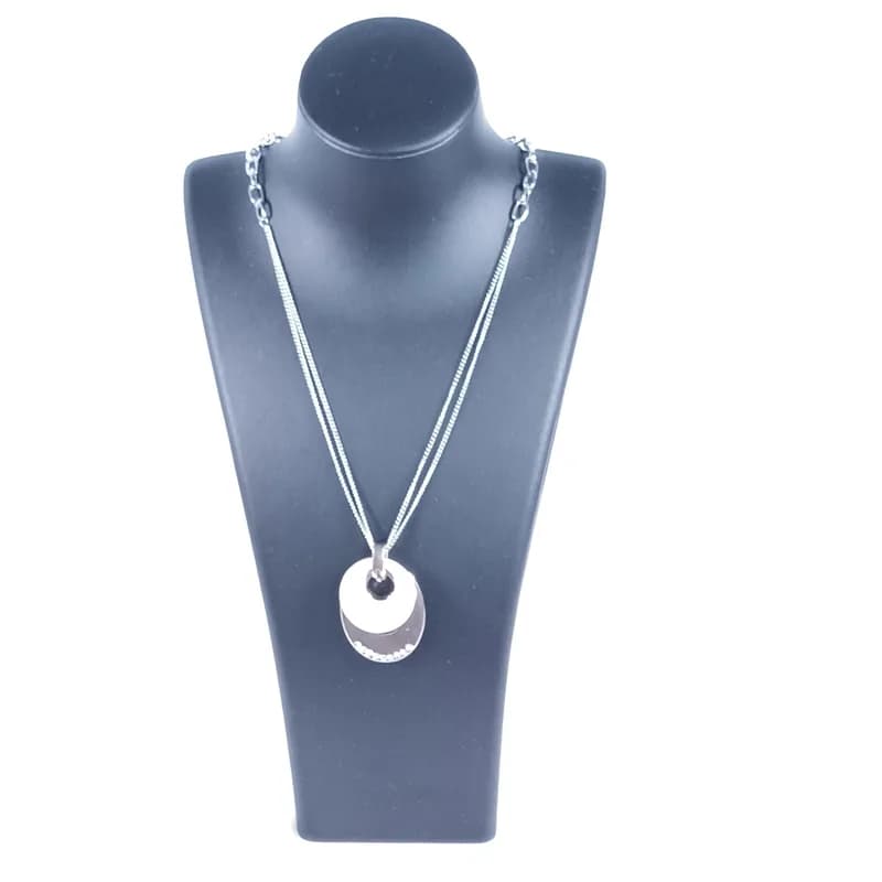 Collier à pendentif ovale ton argenté et disque nacré porté sur un buste noir.