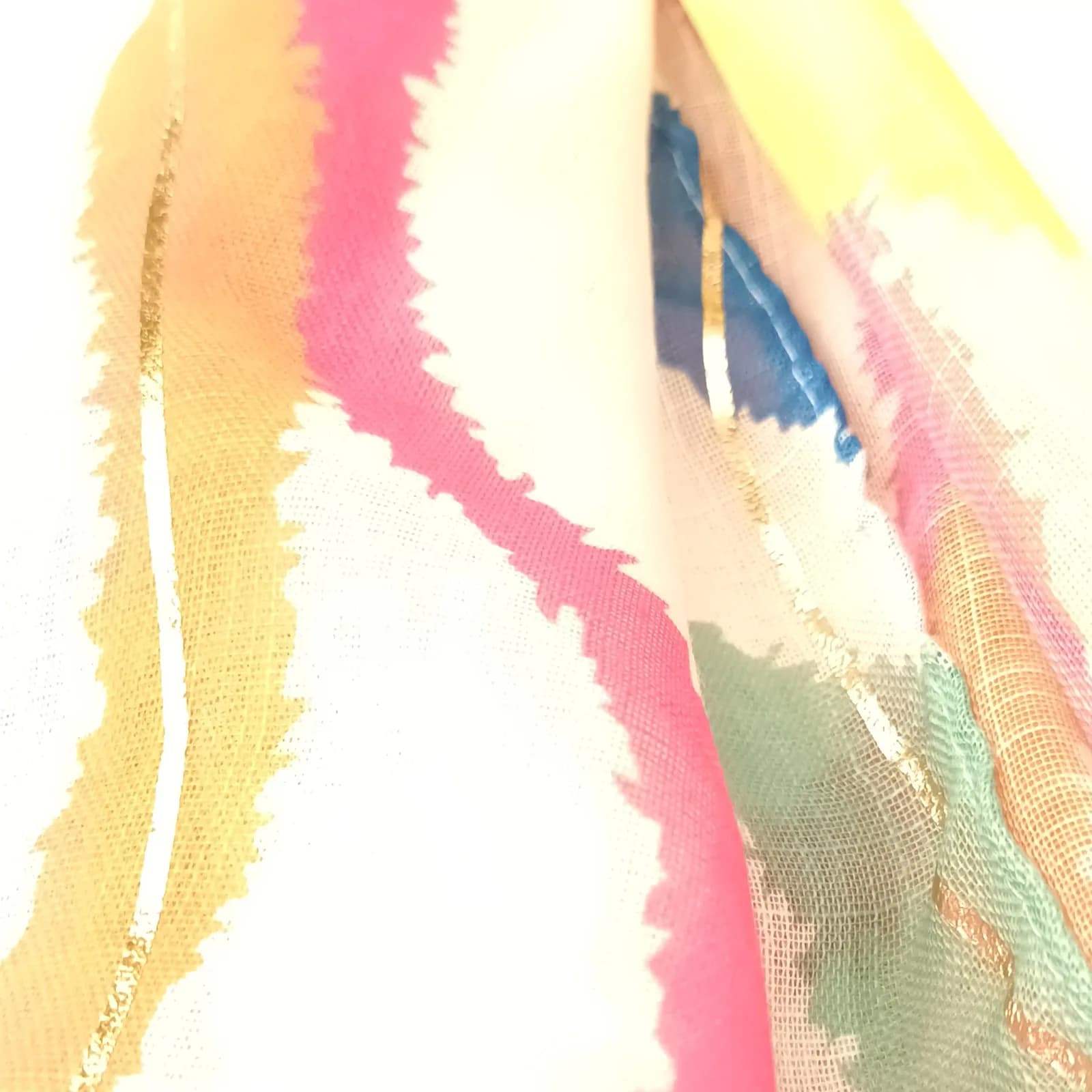 Gros plan sur une ligne dorée et la trame légère du foulard multicolore.