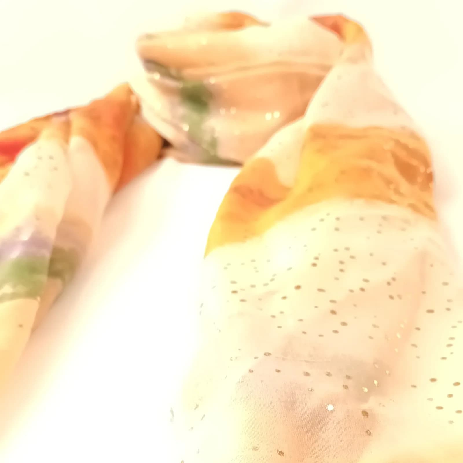 Vue rapprochée du foulard aquarelle orange avec des touches de vert et de lilas.