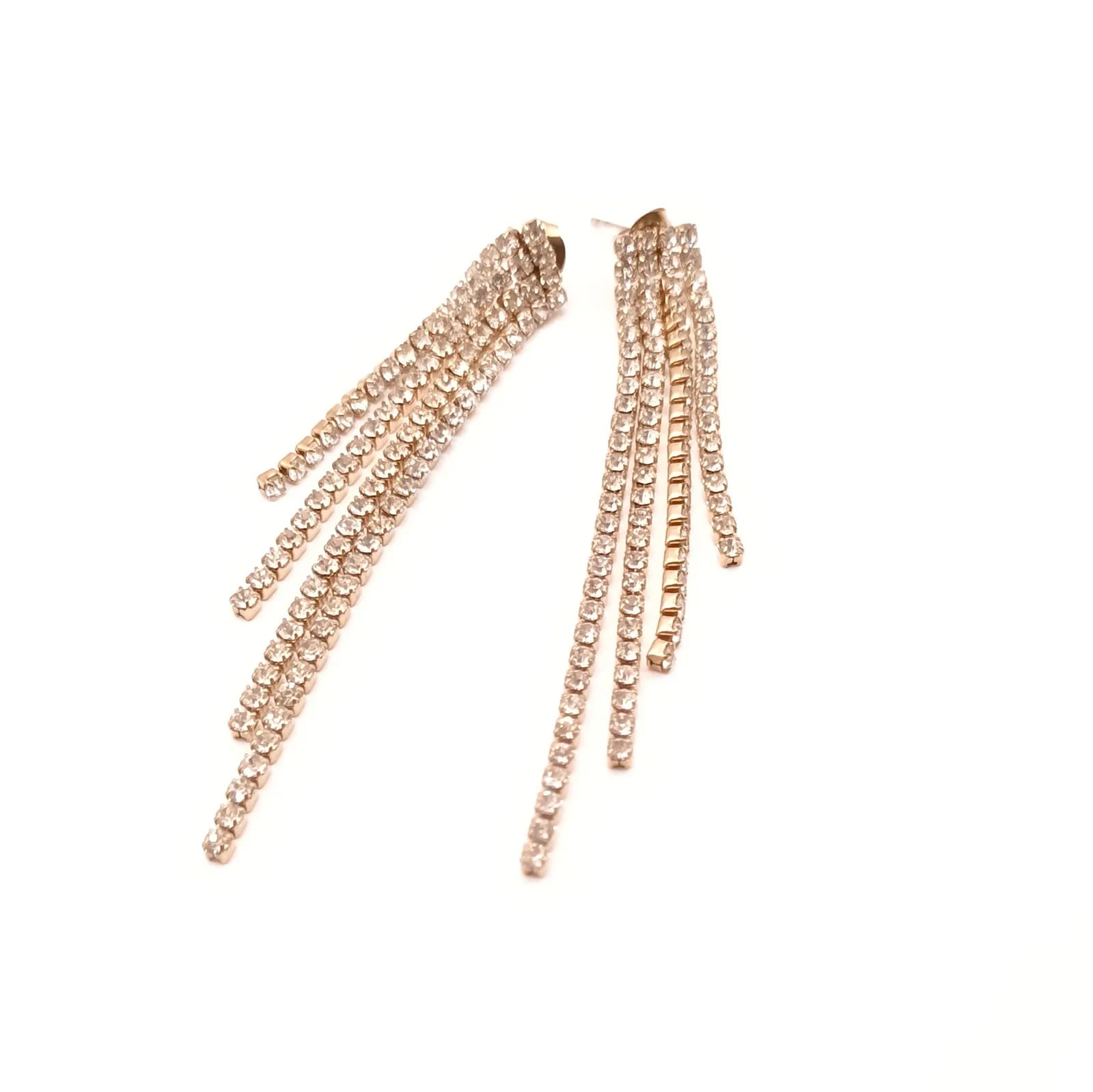 Boucles d'oreilles dorées à franges de longueurs inégales, vues en diagonale sur fond blanc