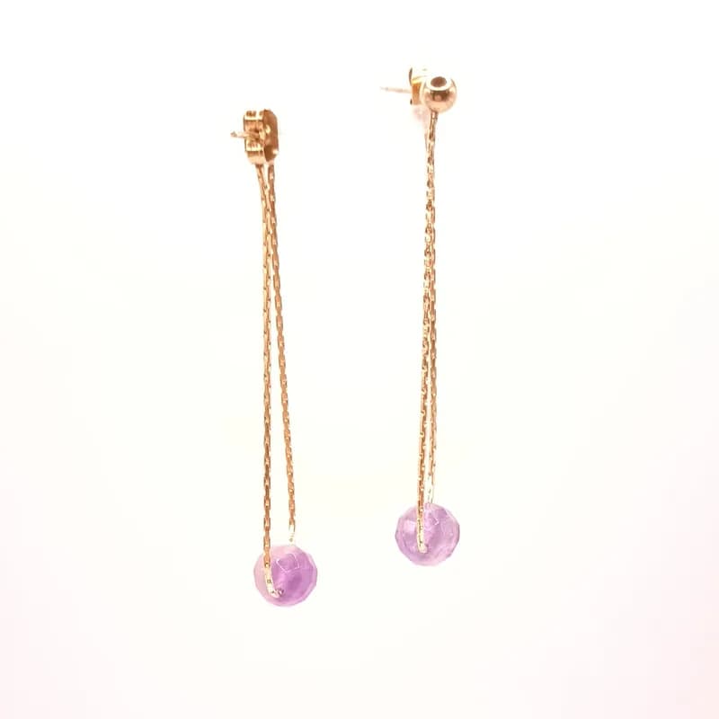 Boucles d'oreilles pendantes par une chaîne dorée et perle violette, vues de face sur fond blanc
