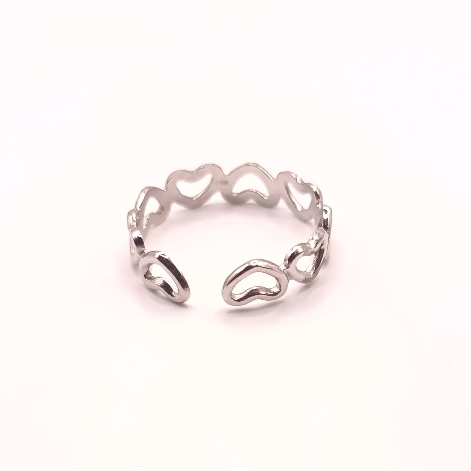 Bague ouverte argentée formée de cœurs ajourés, vue de face sur fond blanc.