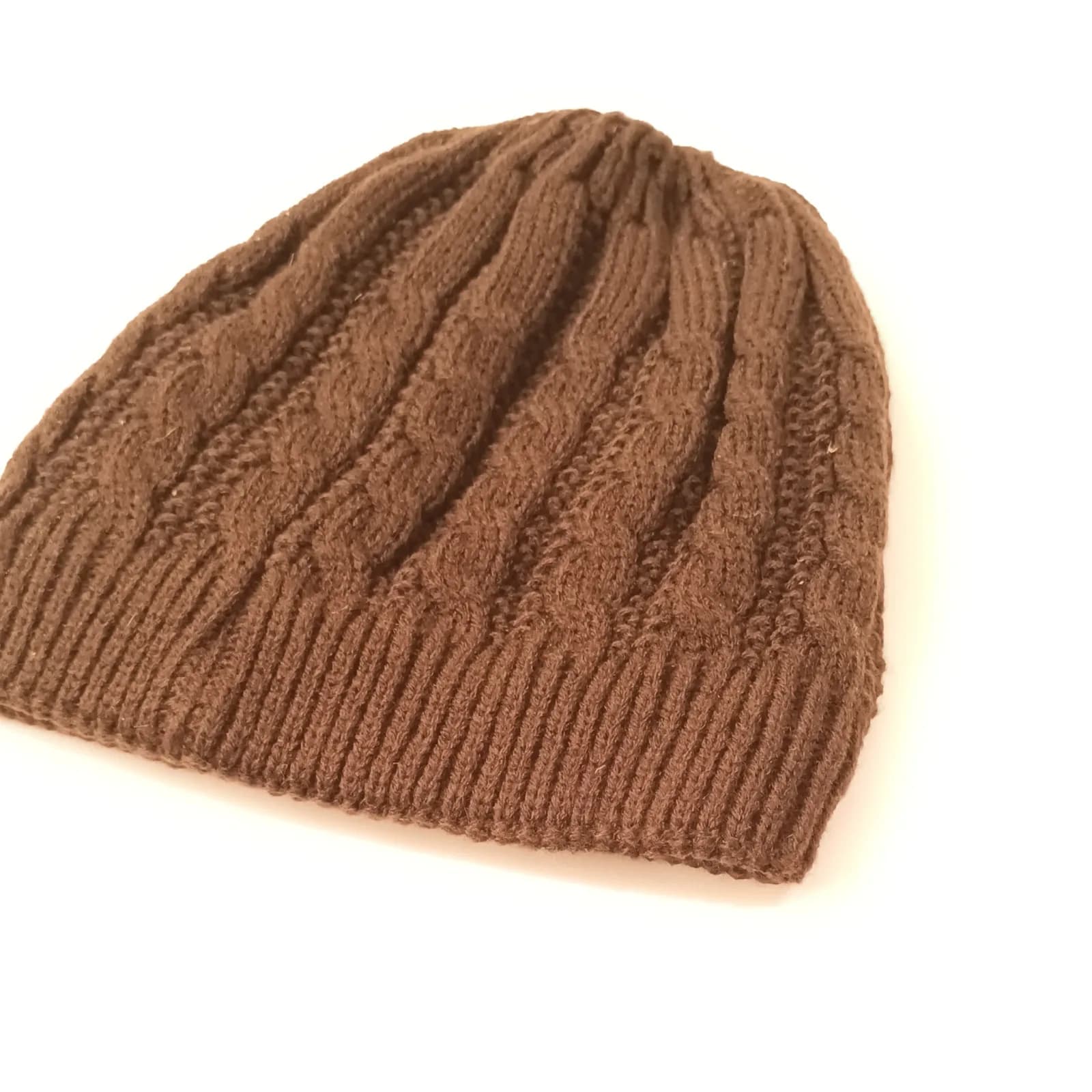 Bonnet marron en maille torsadée, posé de biais sur fond blanc.