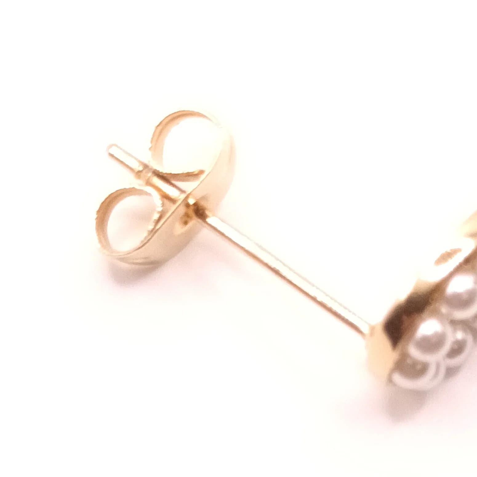 Gros plan sur la tige et le fermoir poussette doré d'une boucle d'oreille infini.