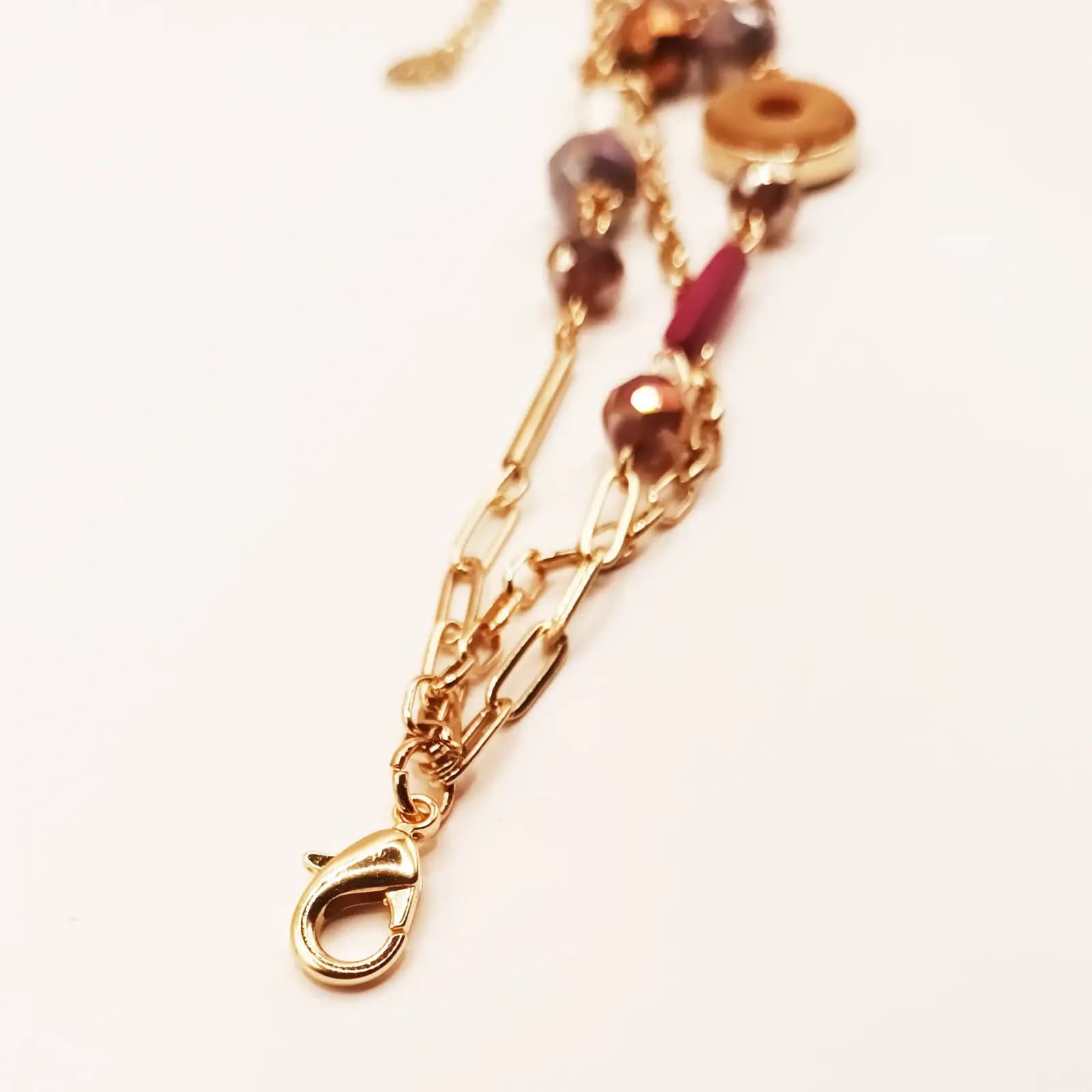 Bracelet triple chaîne dorée à perles facettées et anneau central - gros plan sur le fermoir mousqueton