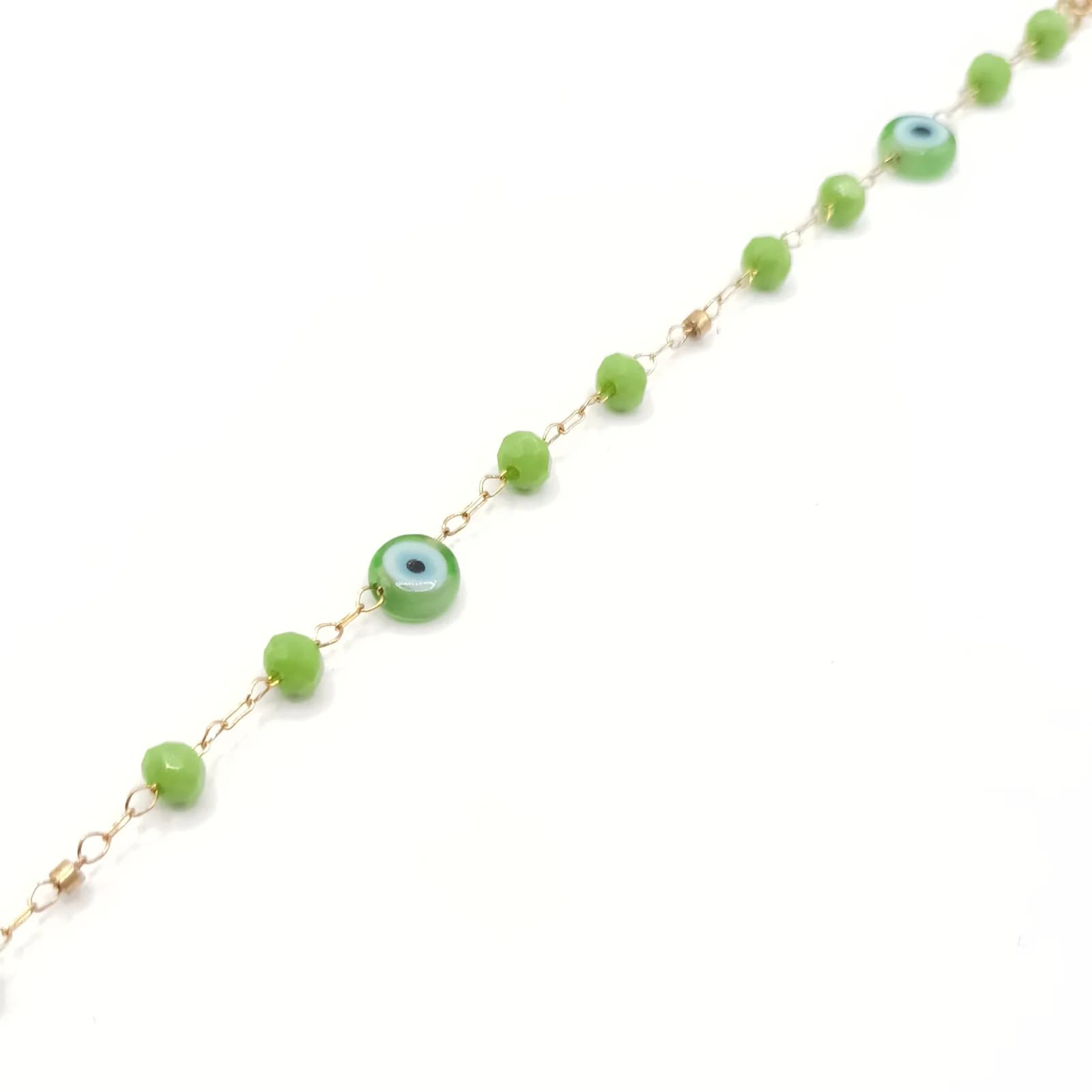 Bracelet doré à perles vertes facettées et yeux protecteurs, posé en diagonale.