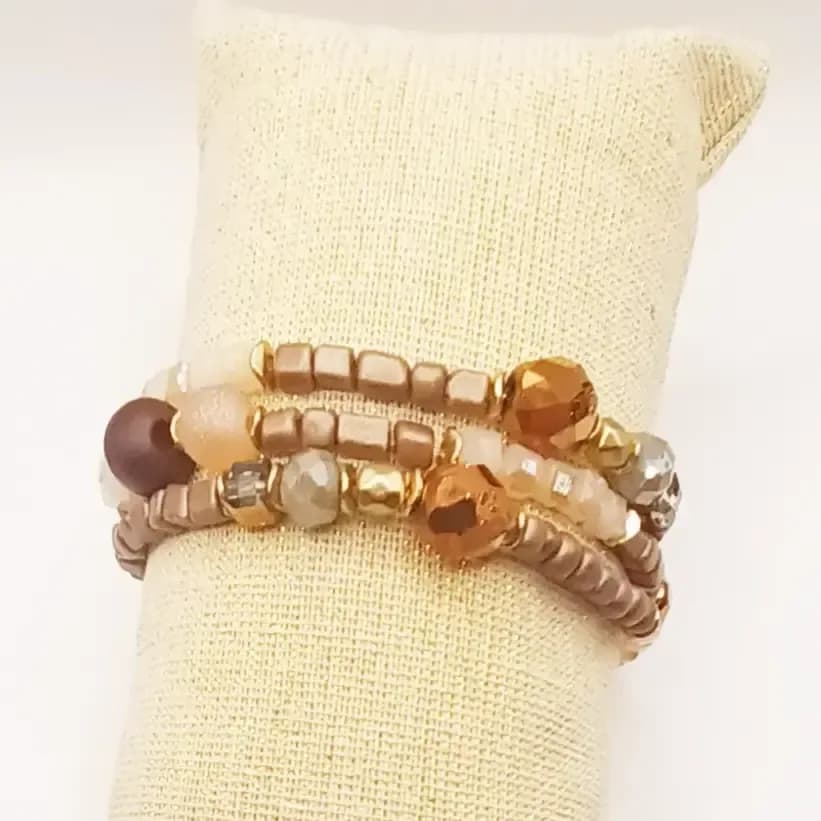 Trio de bracelets en perles marron, beige et cuivrées - porté sur un présentoir en lin, gros plan sur les perles
