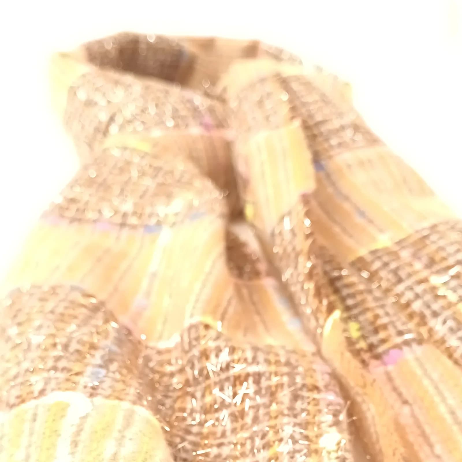 Vue rapprochée floutée des bandes scintillantes de l'écharpe tweed beige.