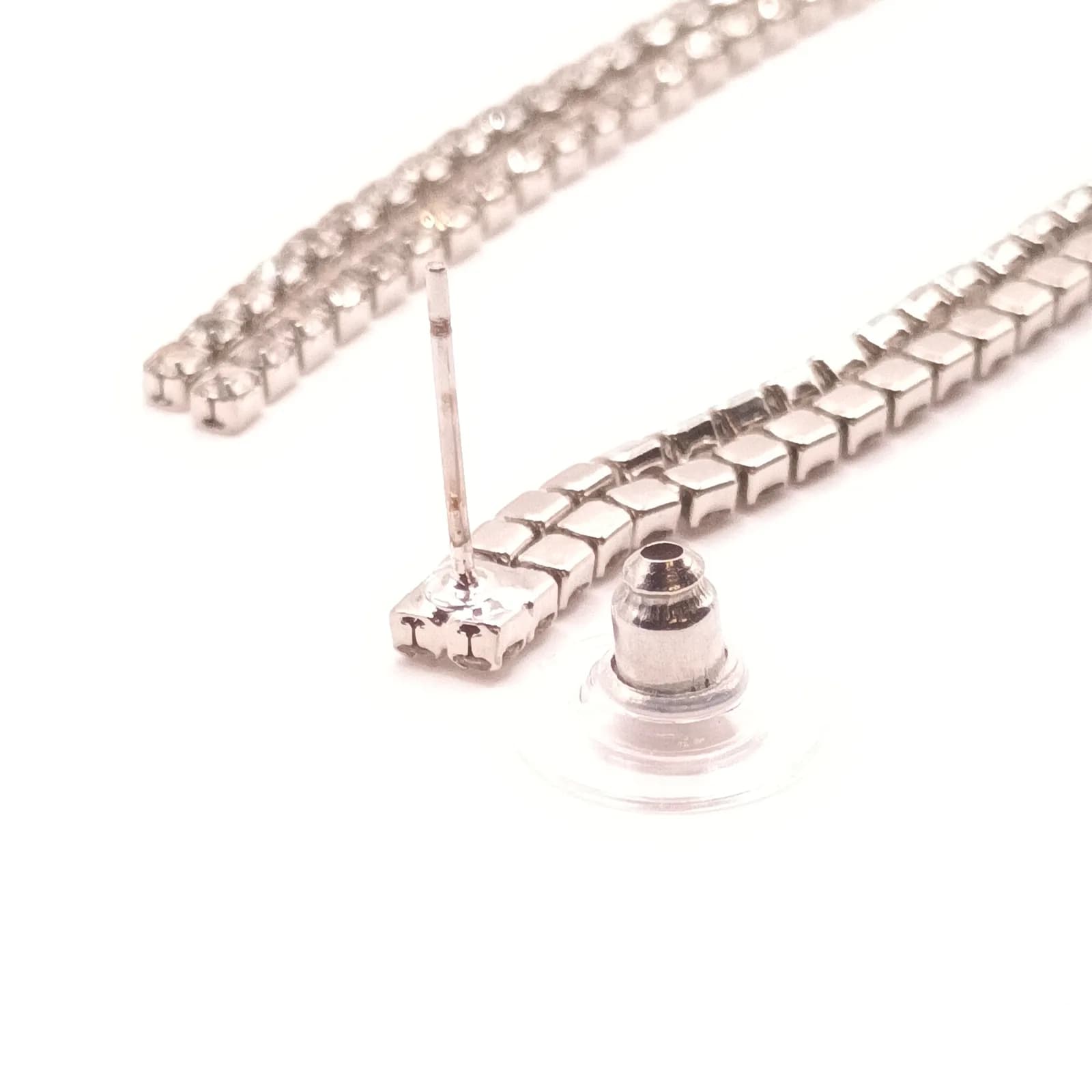 Gros plan sur la tige et le poussoir avec embout transparent d'une boucle d'oreille argentée