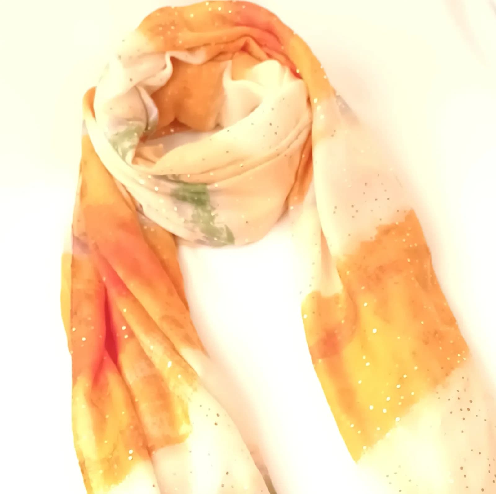 Foulard orange et ivoire à pois dorés, drapé en boucle et vu de biais.
