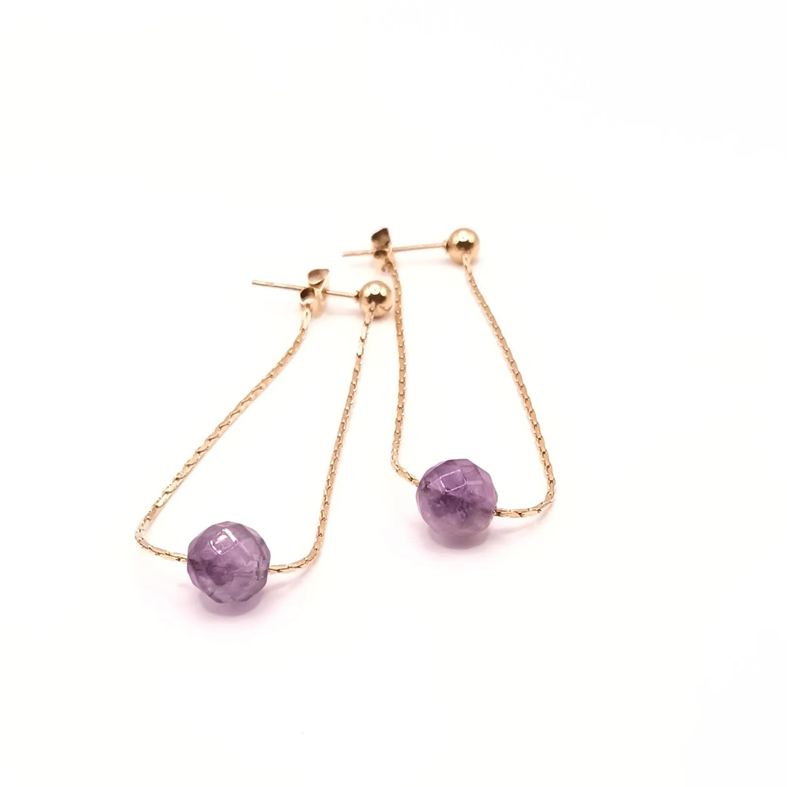 Détail de la perle violette facettée enfilée sur la fine chaîne dorée