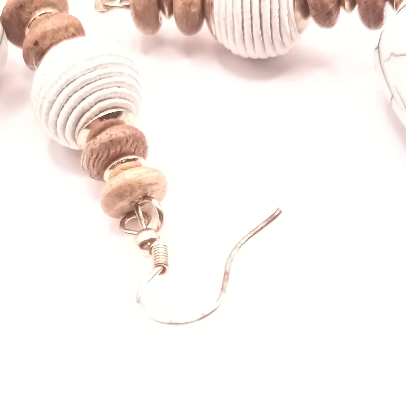 Gros plan sur le crochet et les perles blanches et beige d'une boucle d'oreille