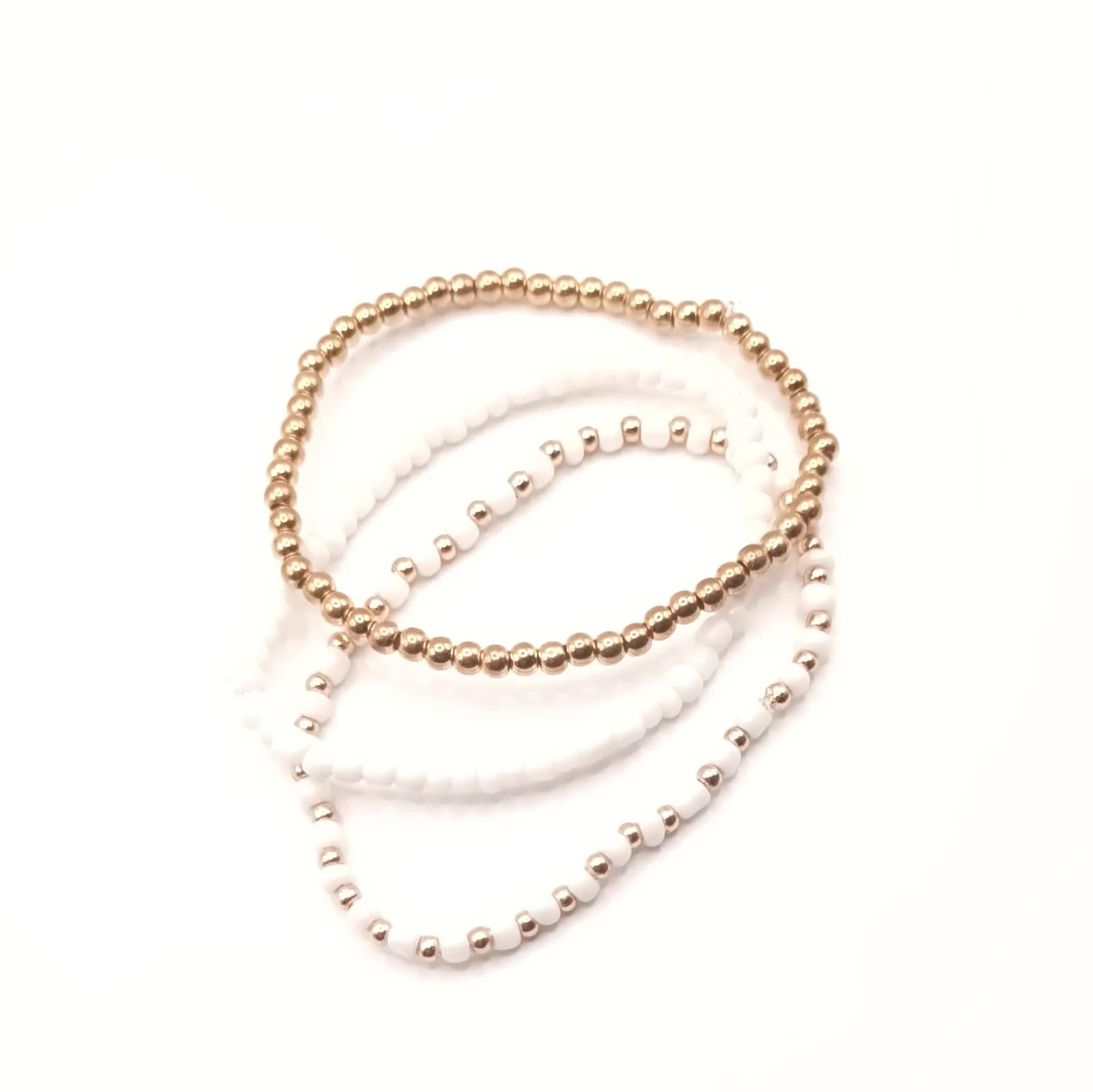 Détail des perles rondes dorées et blanches des trois bracelets